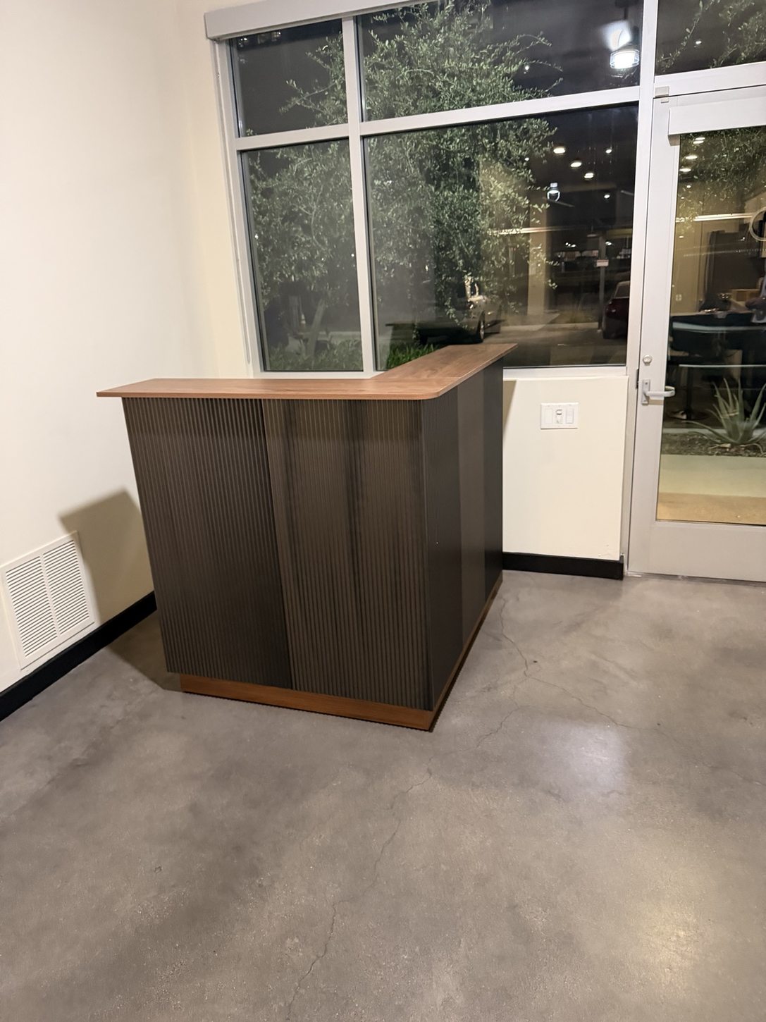 Completed L-shaped dark fluted bar and wood-look counter assembled by BoxBuilt in Tempe